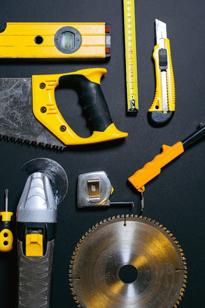 about-us-02 A collection of yellow and black construction tools arranged on a dark flat surface, ideal for DIY projects.